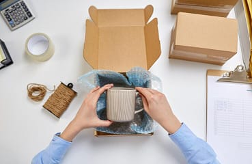 hands-packing-mug-parcel-box-post-office_380164-246704 Corporate Merchandise Gifting